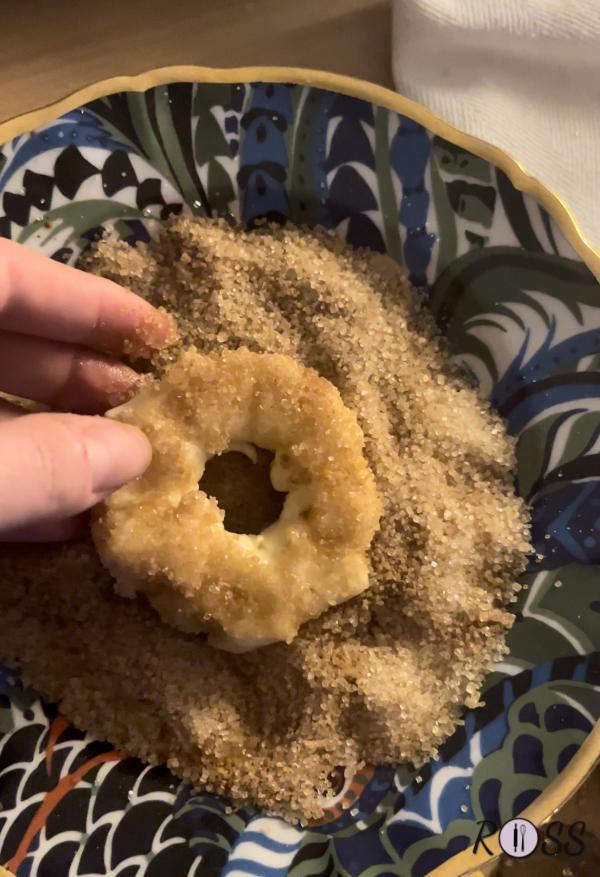 (Dovranno essere passaggi molto rapidi perché il succo della mela scioglierà lo zucchero. Quindi ti consiglio di creare una ciambellina alla volta!)
Nel primo piatto con zucchero e cannella immergi una fetta di mela. Adesso arrotola una strisciolina di pasta sfoglia.
Nel secondo piatto con zucchero e cannella immergi la ciambellina ottenuta ( se lo zucchero non si attacca per bene, bagna la superficie con un pò d'acqua). 