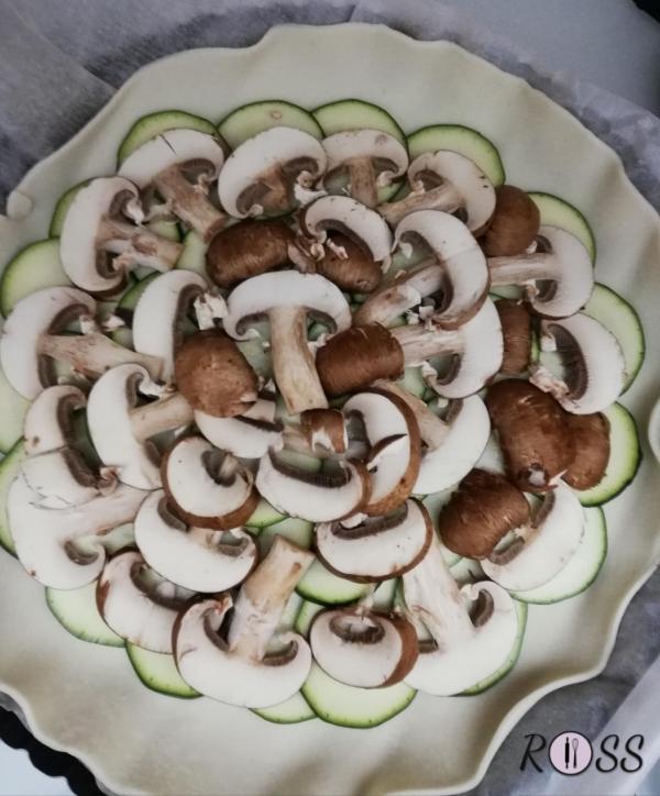 Per prima cosa accendete il forno, modalità ventilata a 180°.
Pulite e tagliate a fette sottili le zucchine e i funghi.
Affettate la provola affumicata.
Prendete una teglia rotonda di 24 cm e ponete sopra la pasta brisèe.
Punzecchiatela con la forchetta ed iniziate a condirla.
Il primo strato di zucchine ed il secondo di funghi. Condite con sale, pepe, origano e olio e proseguite con  il terzo strato di prosciutto e terminate con la provola.