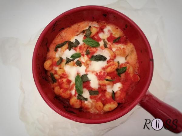 Spegni il fuoco ed elimina lo spicchio d'aglio. Aggiungi gli gnocchi, ricoprendoli di pomodoro, la mozzarella a tocchetti e le foglie di basilico. Prendi una pirofila da forno e travasa qui gli gnocchi conditi. Termina con il parmigiano in superfice. Inforna per 10 minuti. Negli ultimi 2 minuti introduci il grill per creare uno strato croccante. 