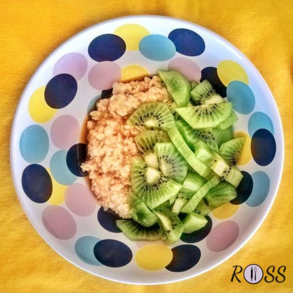 Unite il cucchiaino di sciroppo d'acero o miele liquido al porridge, precedentemente trasferito in una ciotola e tagliate il kiwi a rondelle o a piccoli pezzi e ponetelo sopra ad esso. 