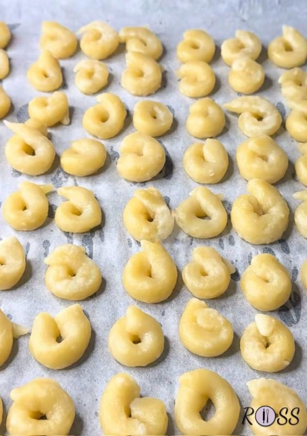 inizia a creare i tuoi taralli, prelevando 15 g di pasta, arrotola fino ad ottenere un cilindro ed unisci i due lembi per creare una ciambellina. Fai così con la restante parte. Dovrai ottenere circa 35 taralli.